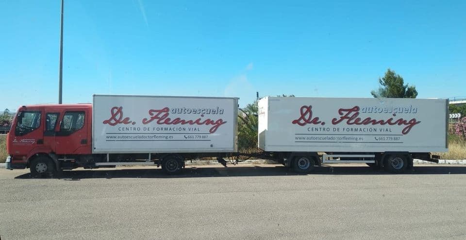 Camión con remolque de la Autoescuela Doctor Fleming, rotulado con el logotipo y el teléfono
